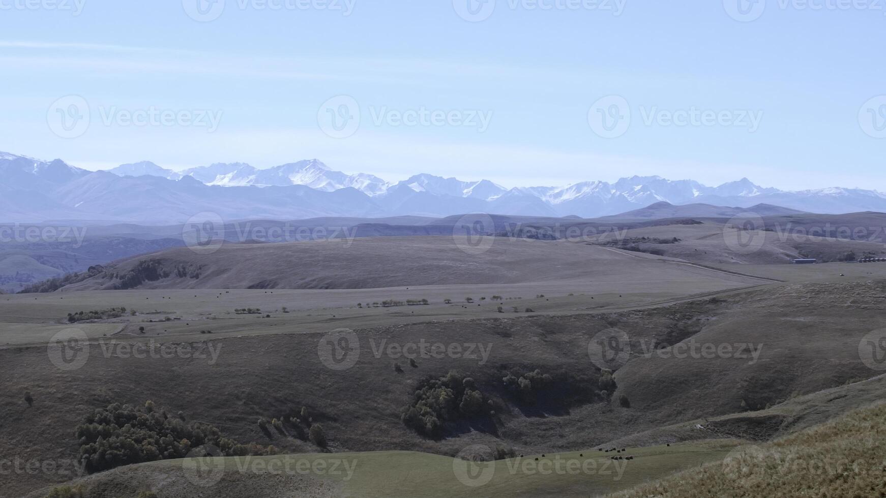 Empty fields and mountains taken from a helicopter. Creative. Large hilly expanses on the road where a tractor rides against the blue sky photo