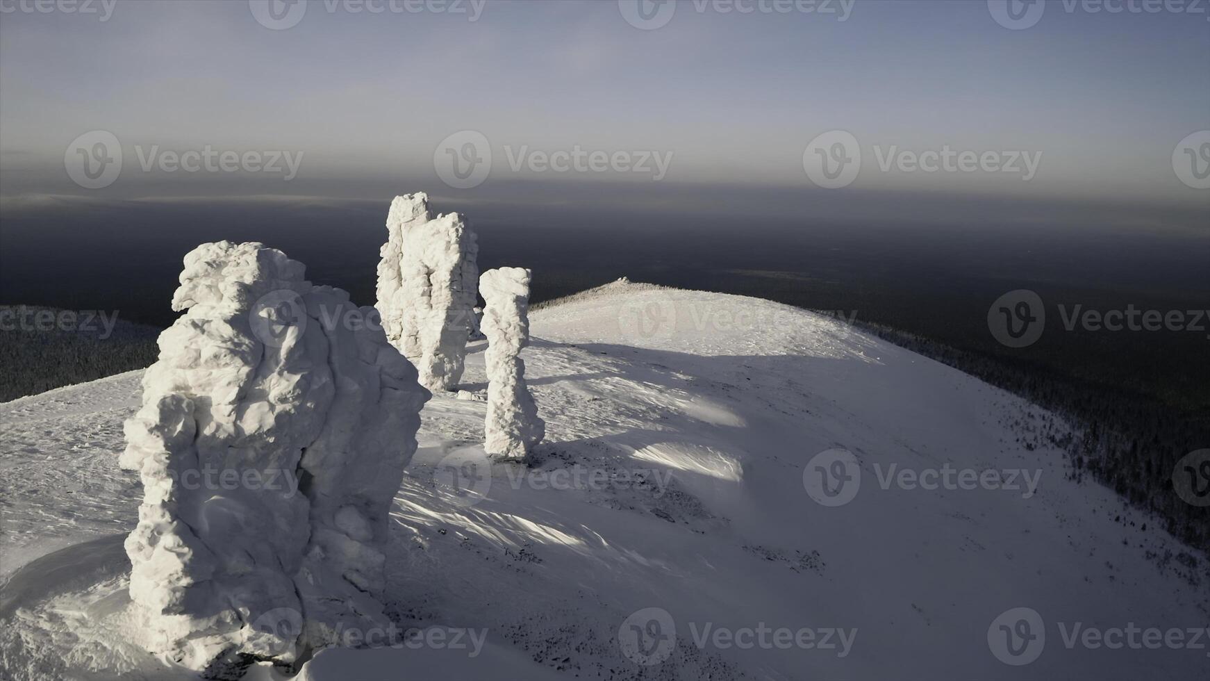 Winter mountain view from a bird's-eye view. Clip.Big mountains under snow and ice on a snowy mountain and a green forest with tall trees is visible below. photo