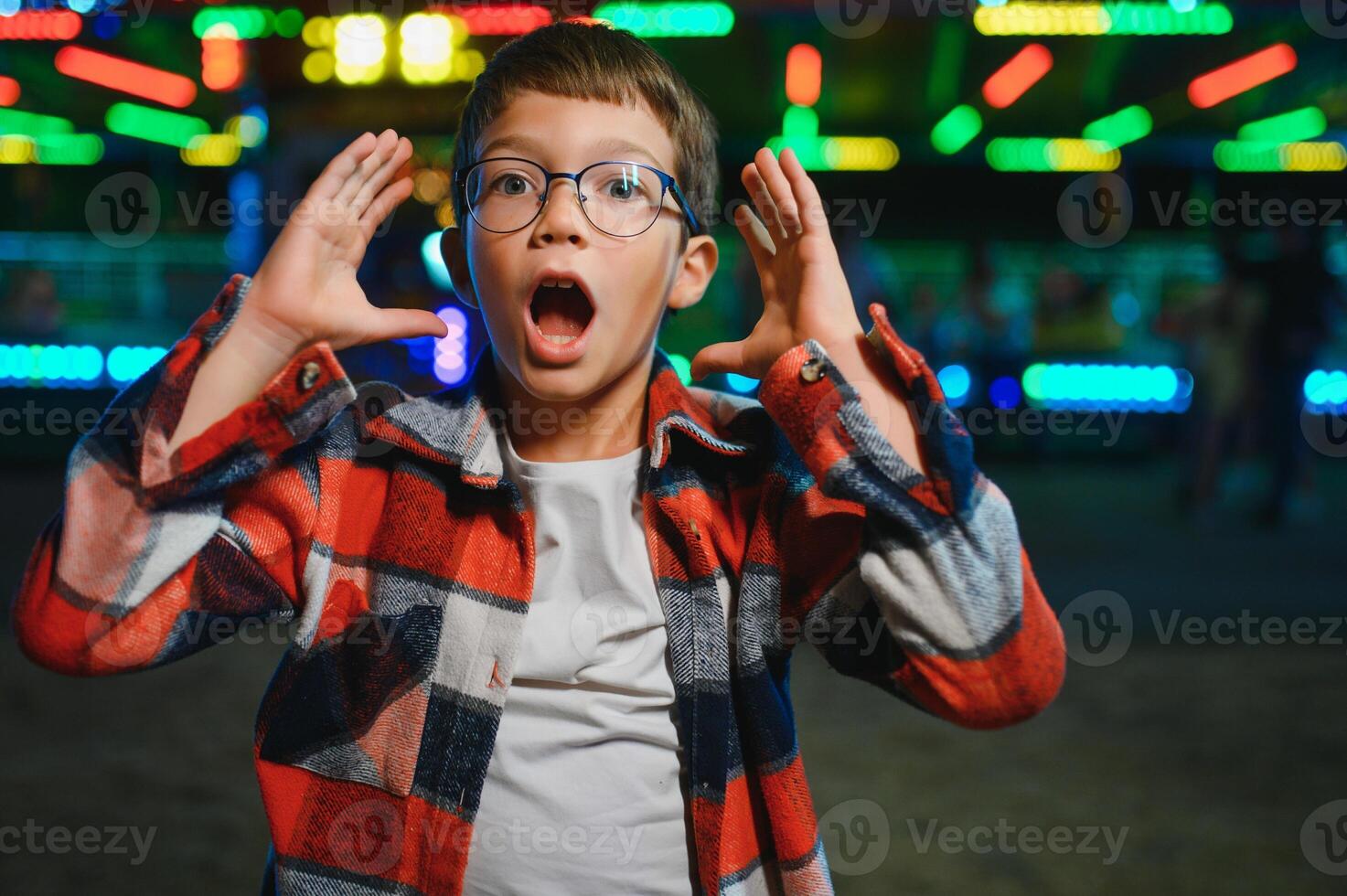 A cute boy happily spends time in an amusement park. Concept of happy childhood and holidays. photo
