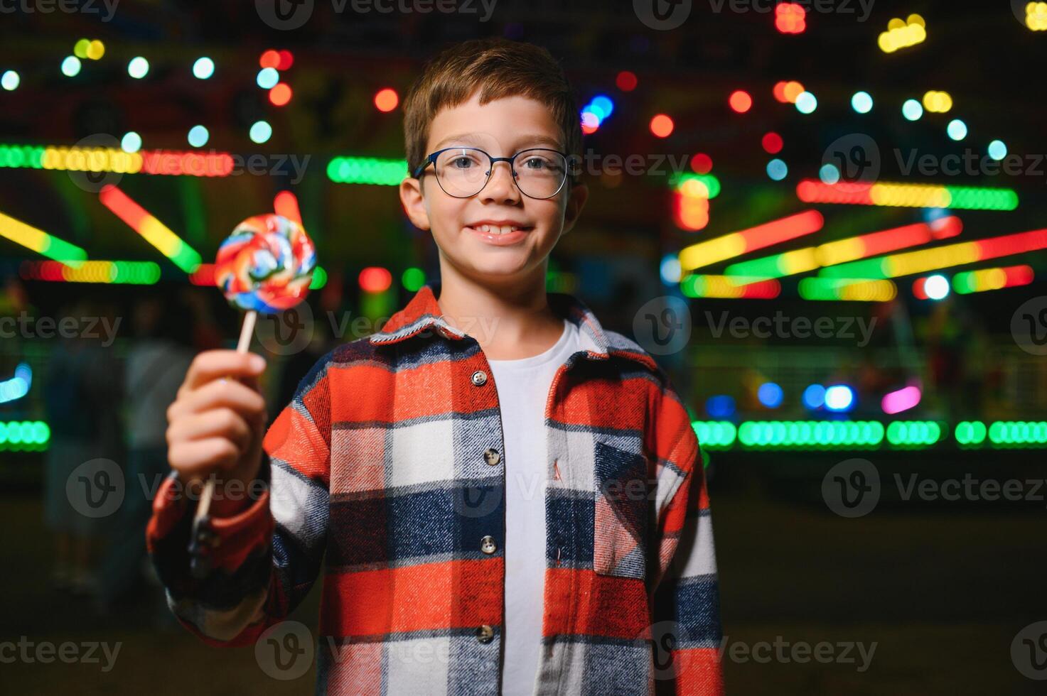 A cute boy happily spends time in an amusement park. Concept of happy childhood and holidays. photo
