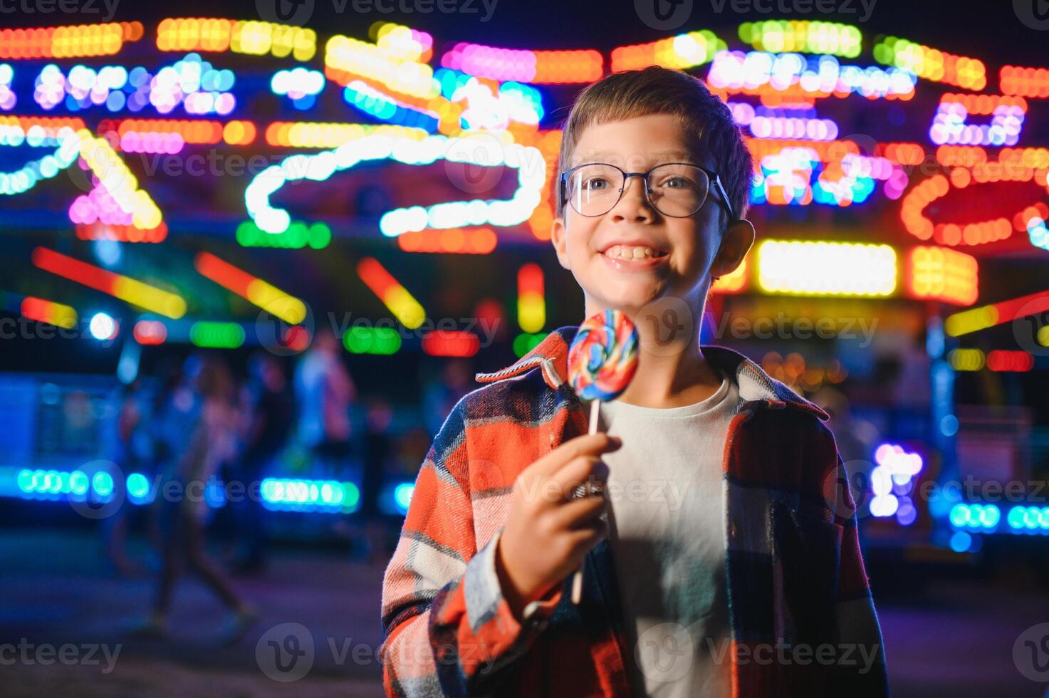 A cute boy happily spends time in an amusement park. Concept of happy childhood and holidays. photo