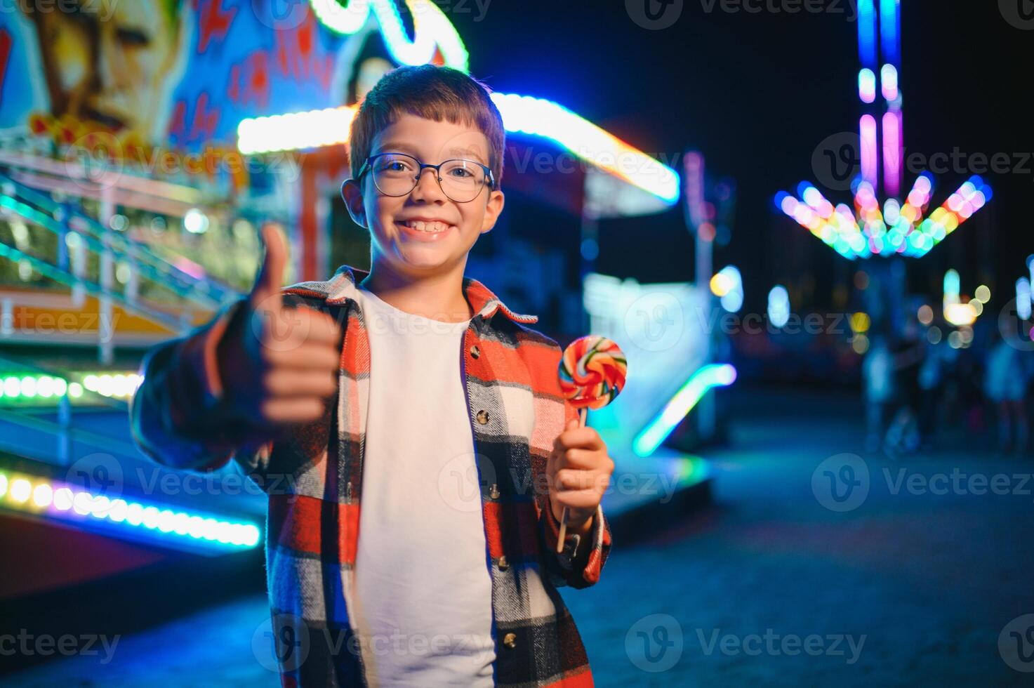 A cute boy happily spends time in an amusement park. Concept of happy childhood and holidays. photo