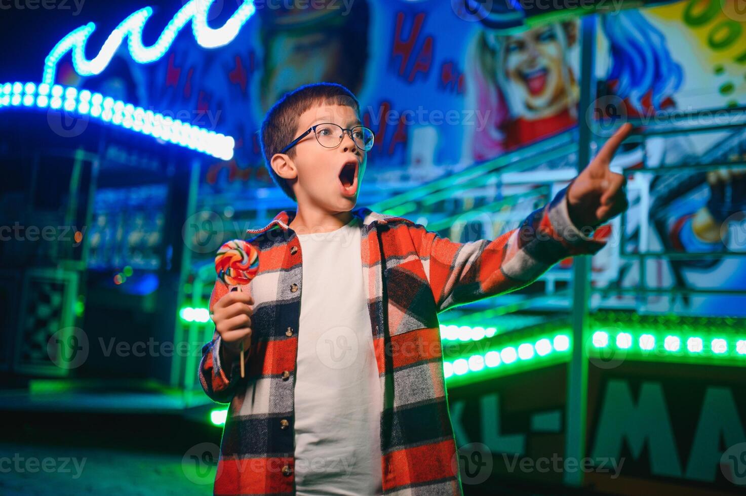 A cute boy happily spends time in an amusement park. Concept of happy childhood and holidays. photo
