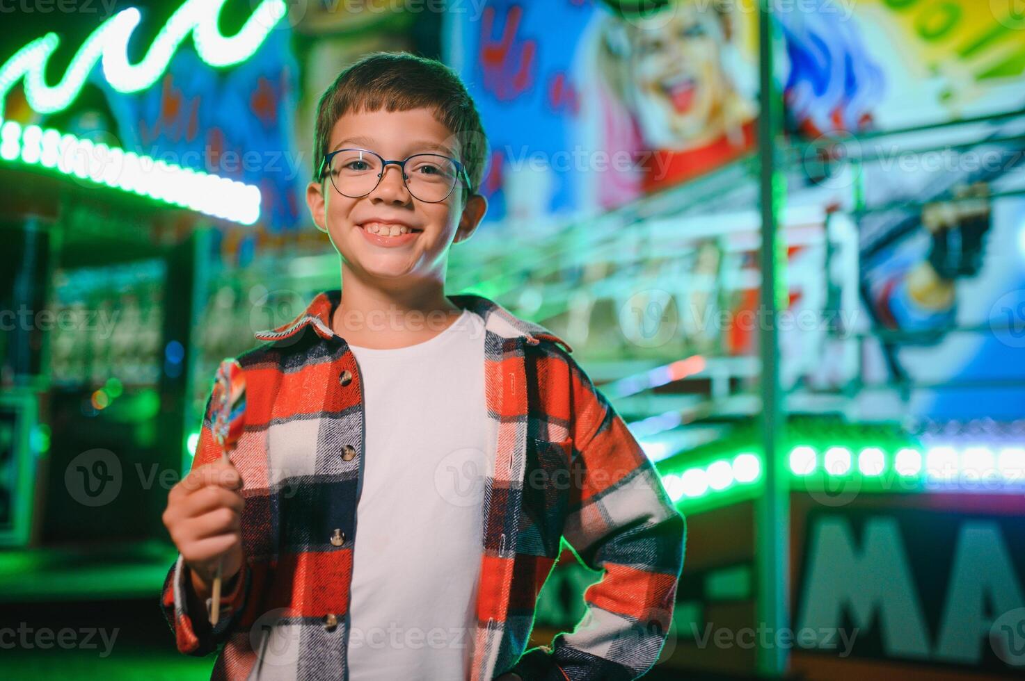 A cute boy happily spends time in an amusement park. Concept of happy childhood and holidays. photo