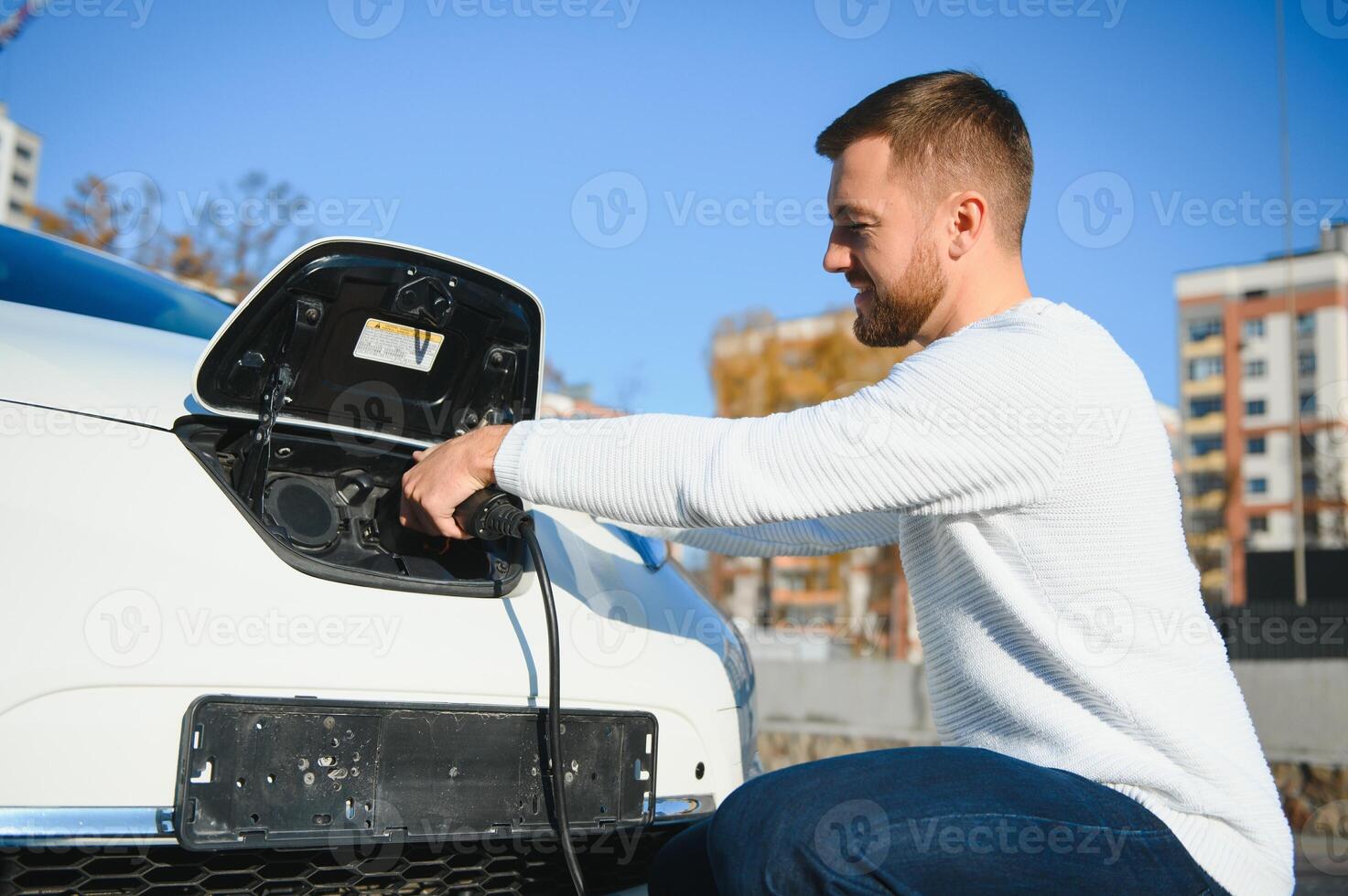 Smiling man unplugging the charger from the car photo