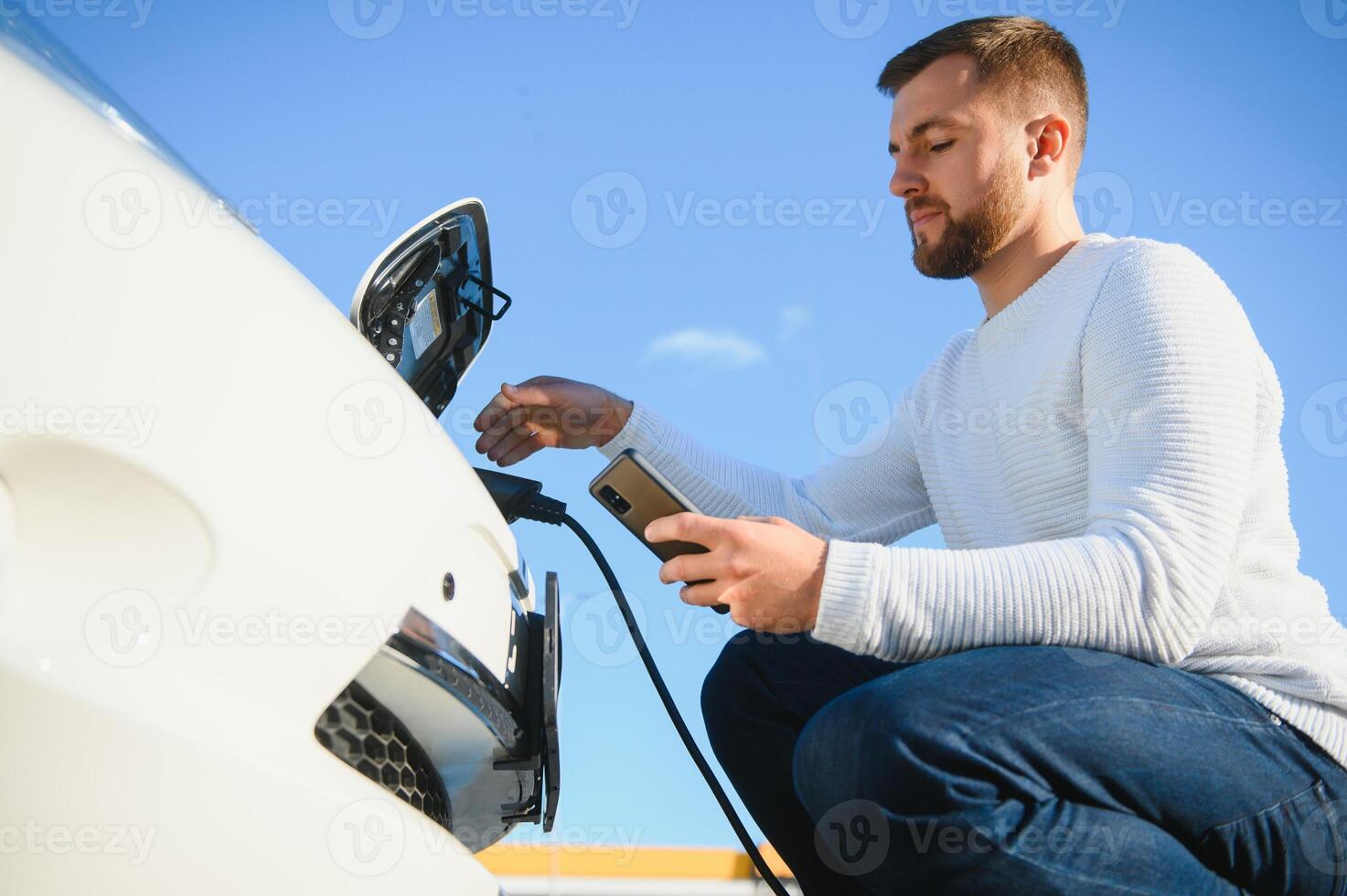 Man charges an electric car at the charging station photo