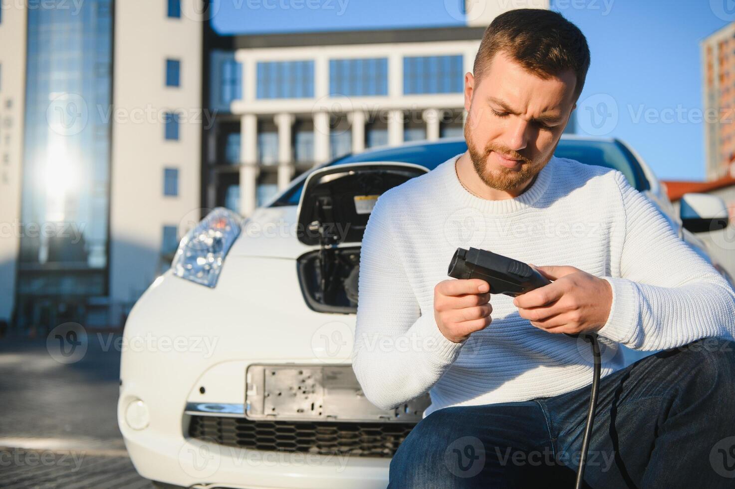 Man charges an electric car at the charging station photo