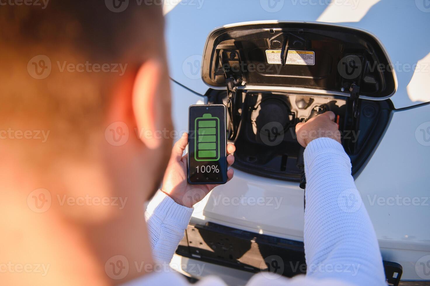 Smartphone app shows charging status of the electric car battery. Electro transport concept photo