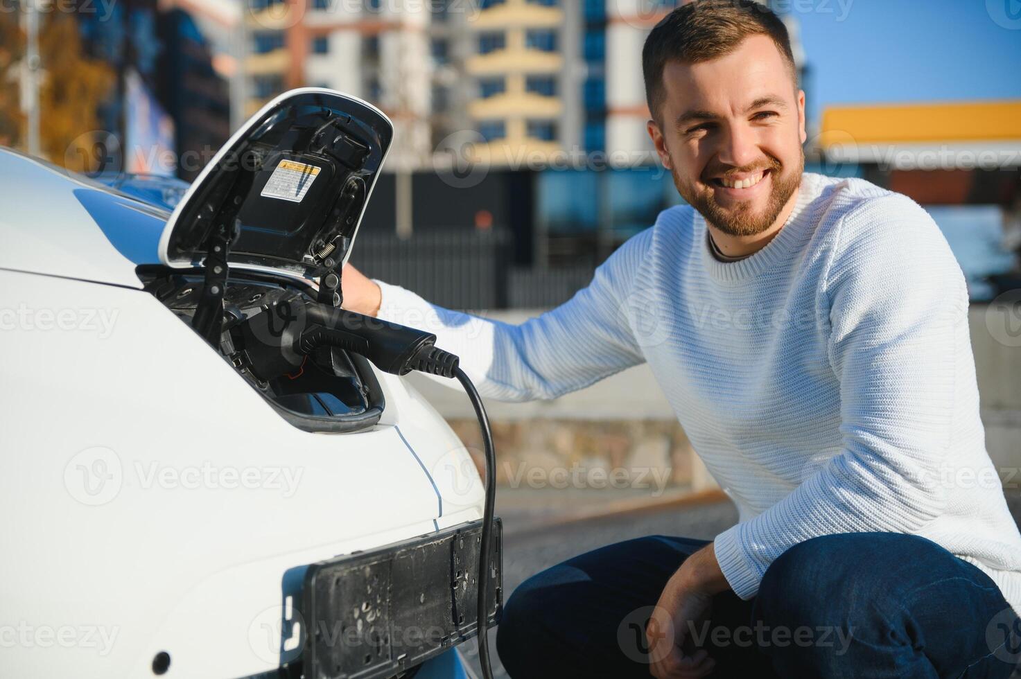Smiling man unplugging the charger from the car photo