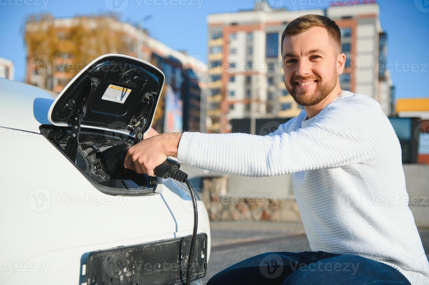 Man charges an electric car at the charging station photo