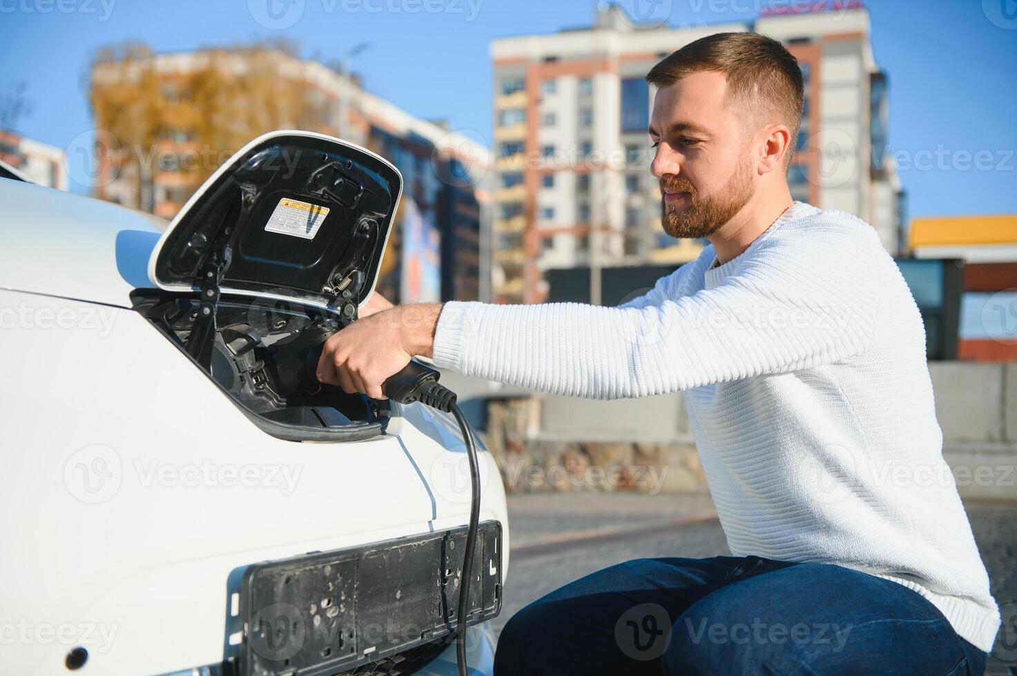 Smiling man unplugging the charger from the car photo