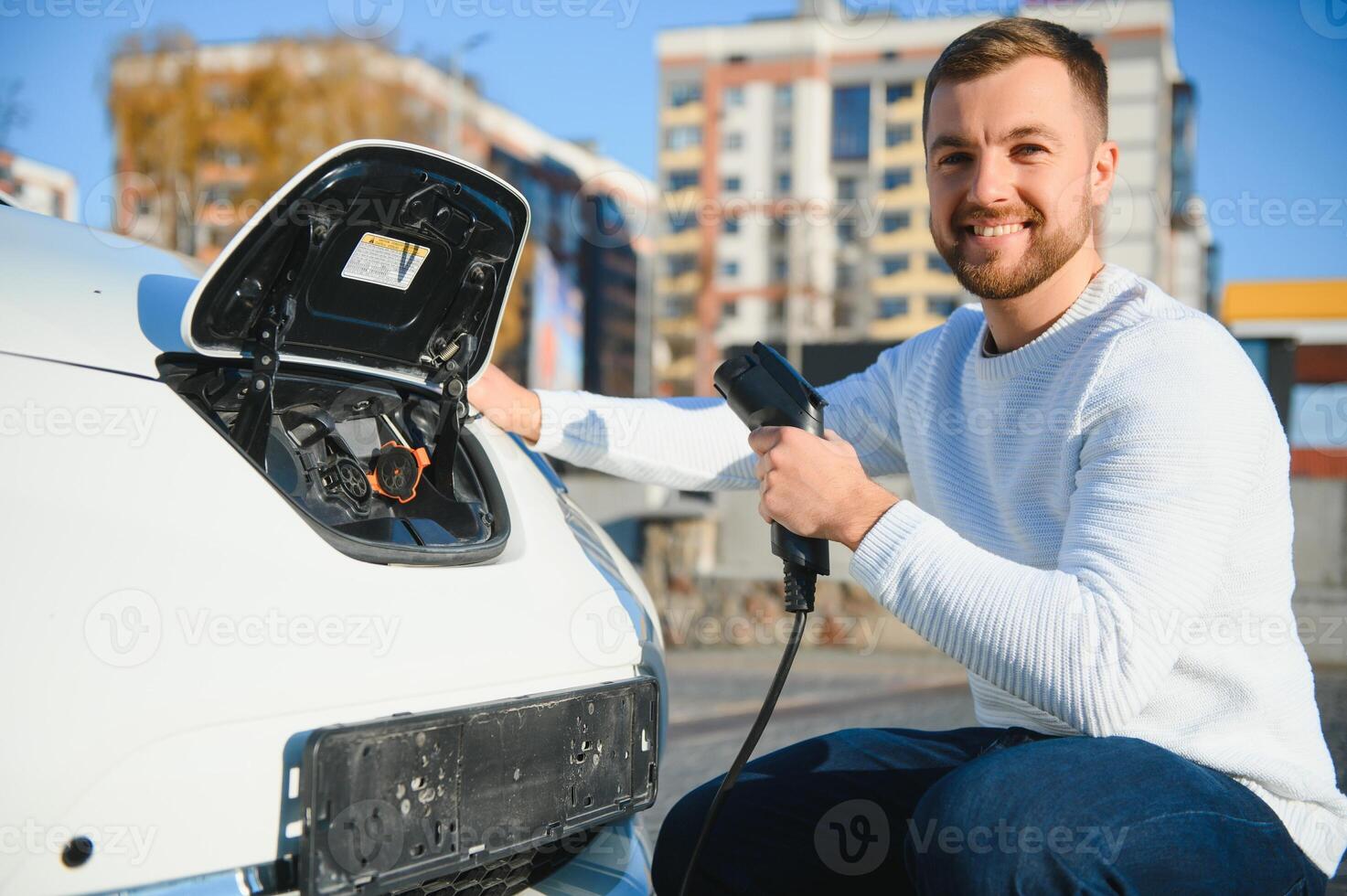 Man charges an electric car at the charging station photo