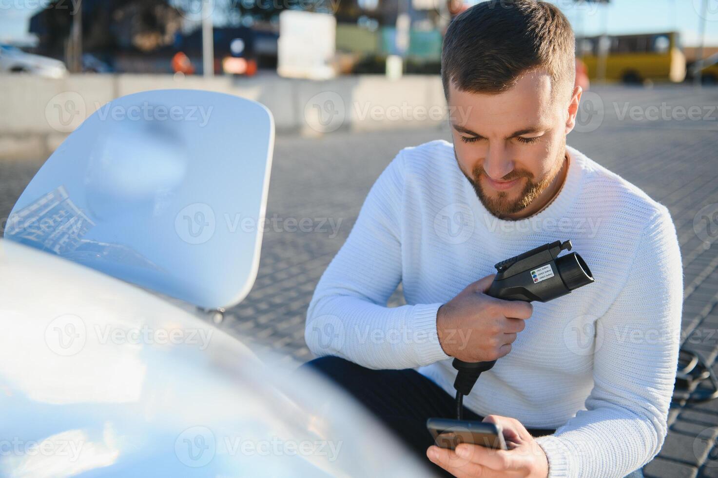 Smiling man unplugging the charger from the car photo
