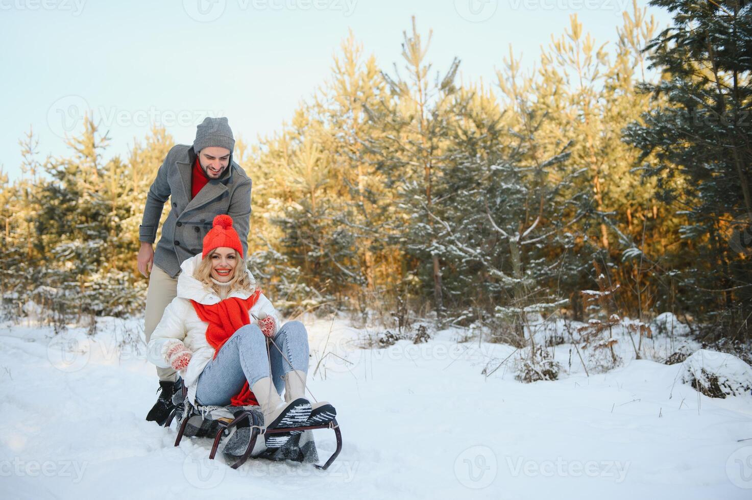 A side view of a happy couple having fun while sliding downhill together over snowy slope using a sled photo