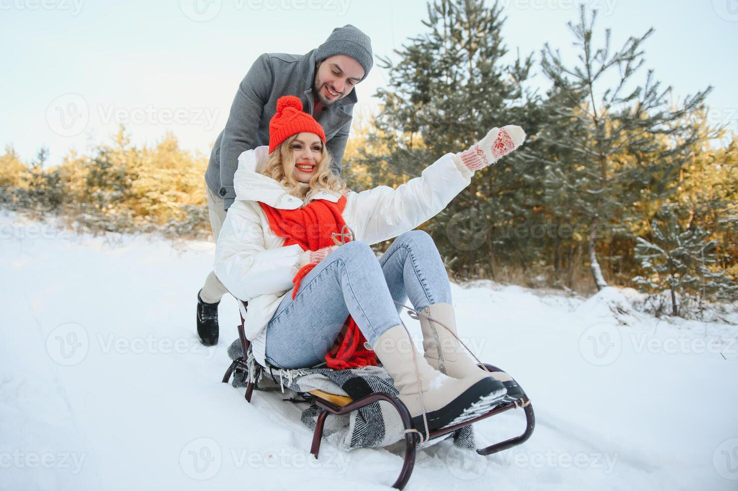 Beautiful young couple in love having fun on a winter vacation in mountains, boyfriend pushing girlfriend on a sled, enjoying snowy, foggy winter day outdoor photo
