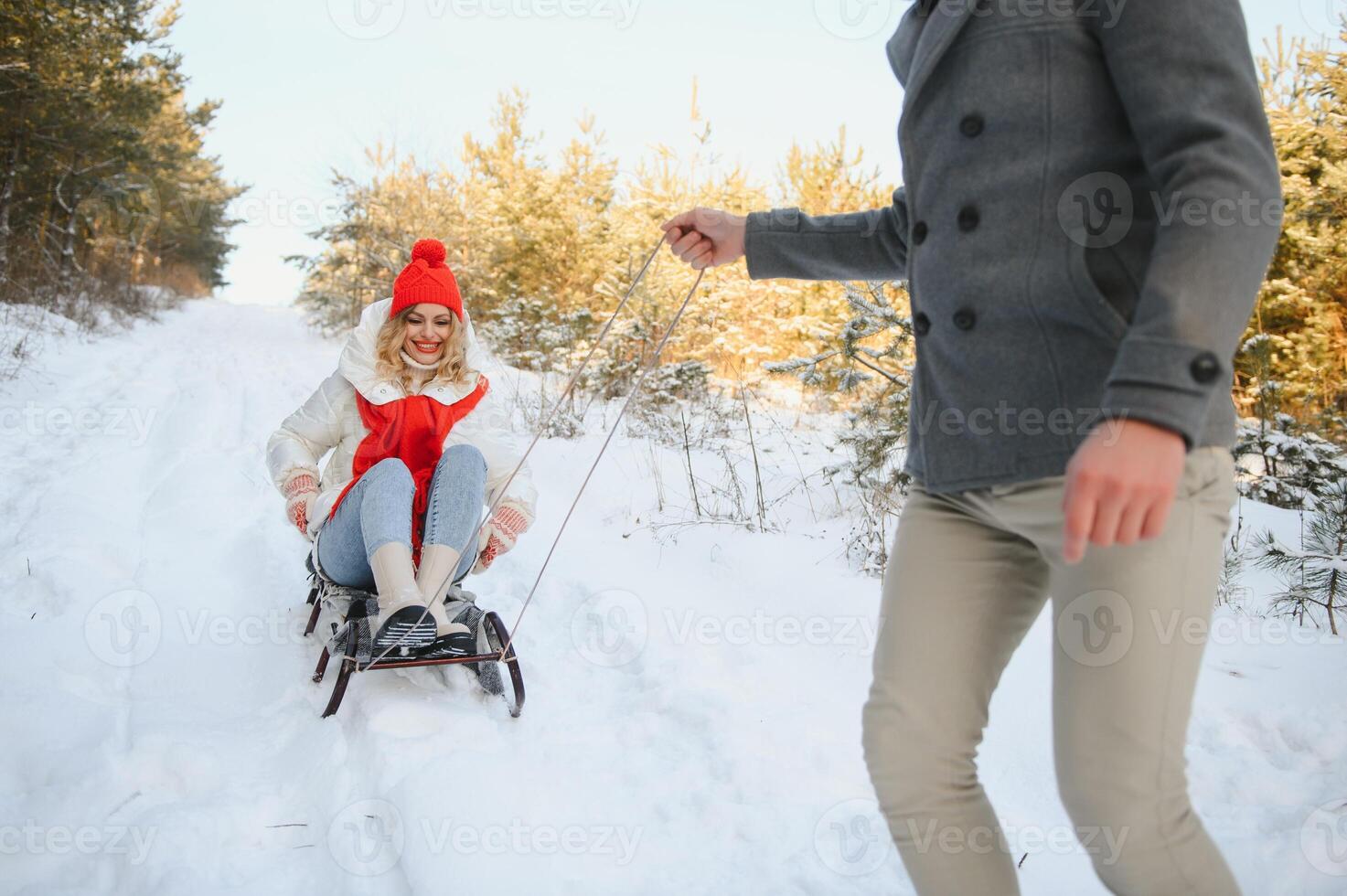 Beautiful young couple in love having fun on a winter vacation in mountains, boyfriend pushing girlfriend on a sled, enjoying snowy, foggy winter day outdoor photo