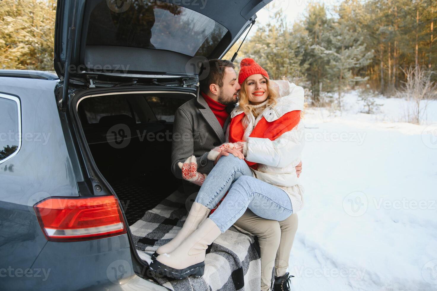 Happy couple sitting in open car back, having stop off. Romantic traveling concept. Winter forest. photo