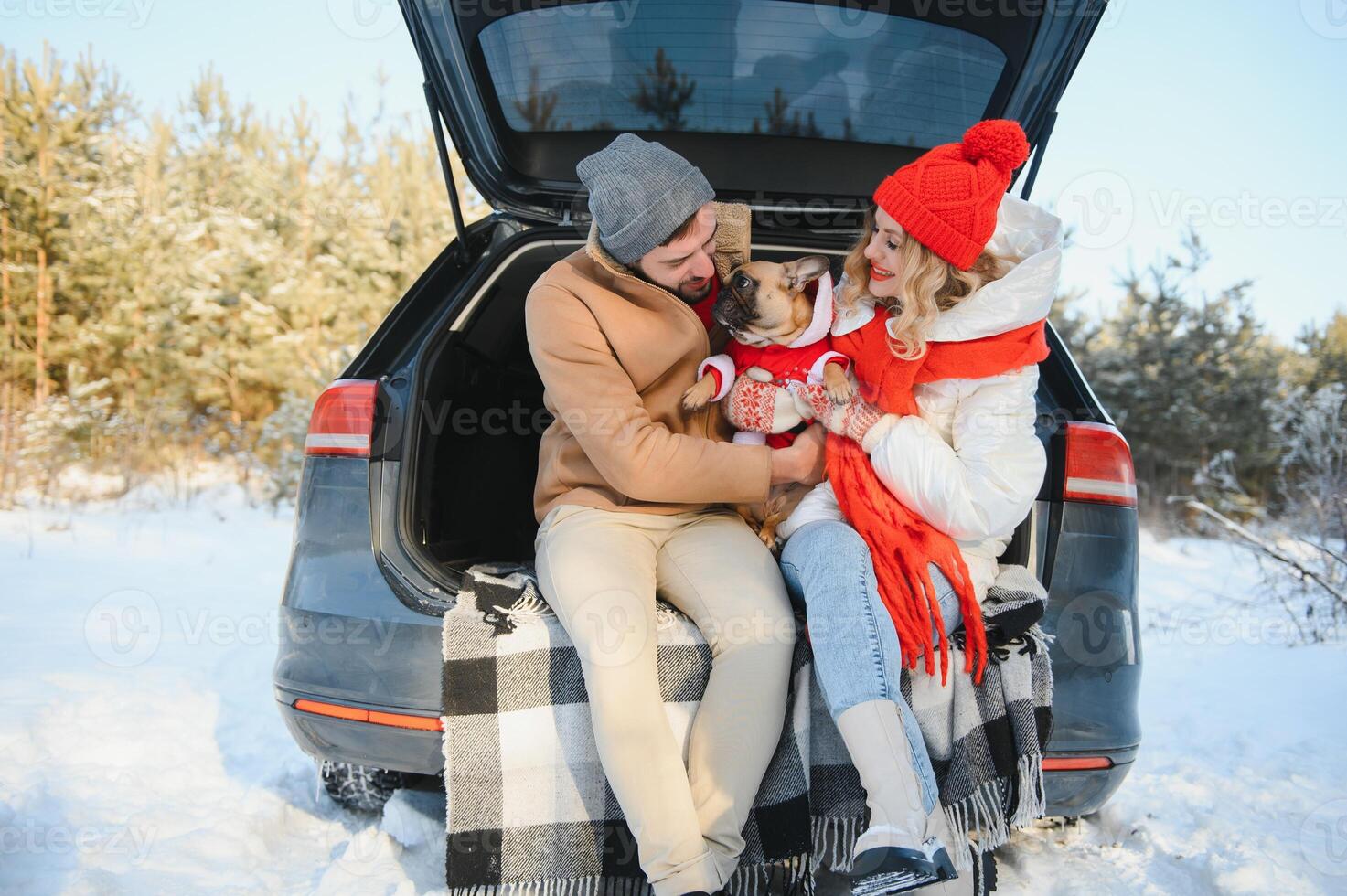 couple guy and girl sitting in car playing with dog in winter forest photo