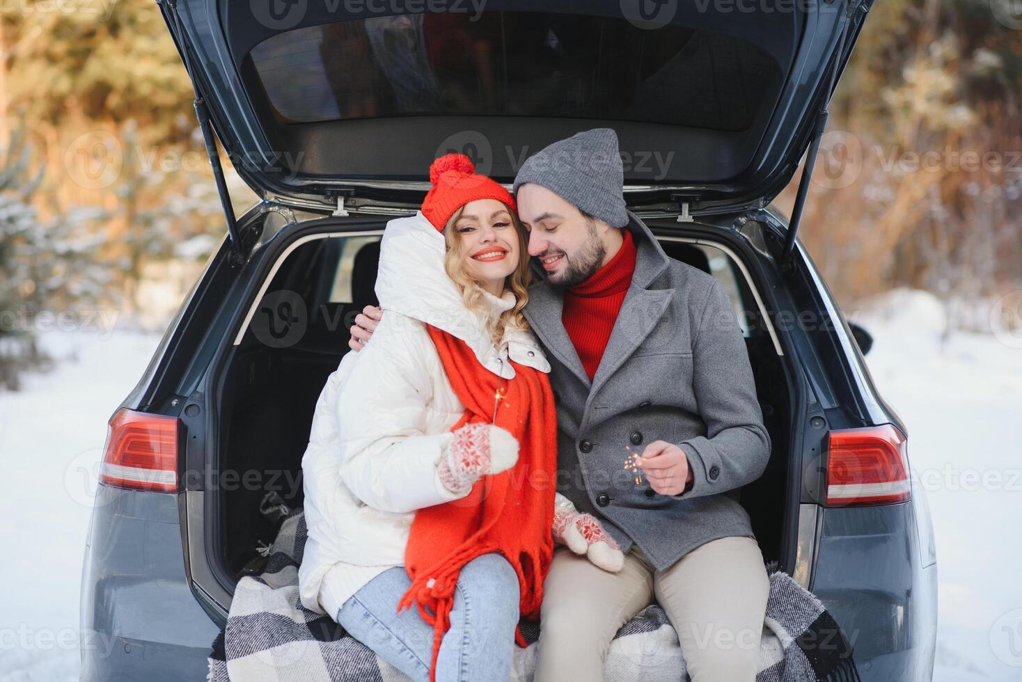 Smiling together. Nice couple have weekend at countryside at winter time. Sitting on the rear part of modern car. photo