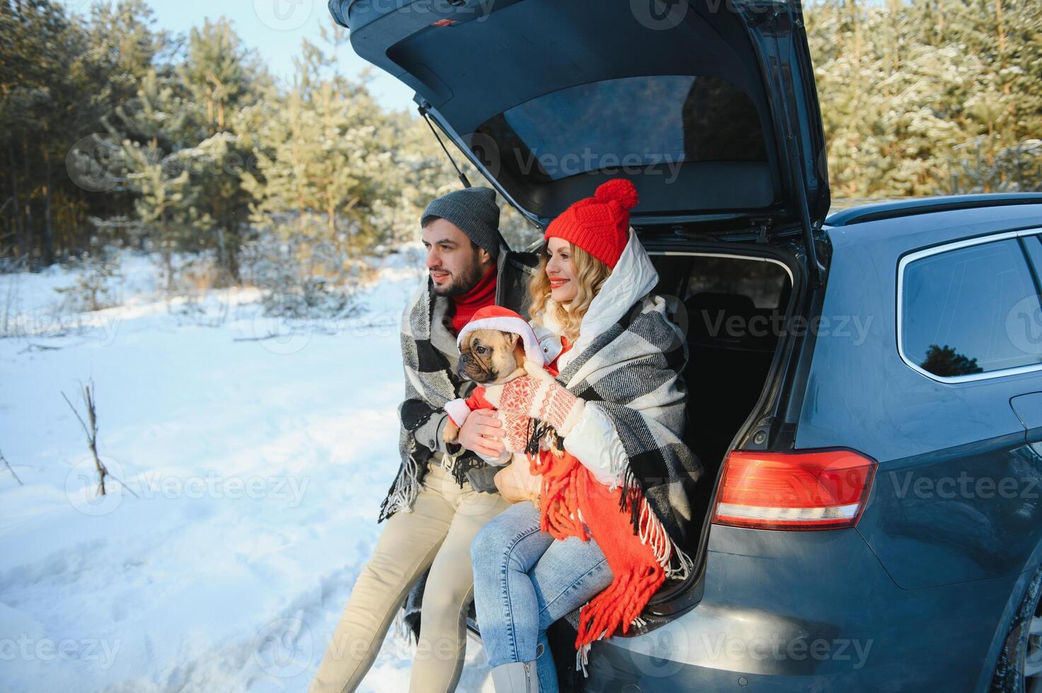 Happy couple sitting in open car back, having stop off. Romantic traveling concept. Winter forest. photo