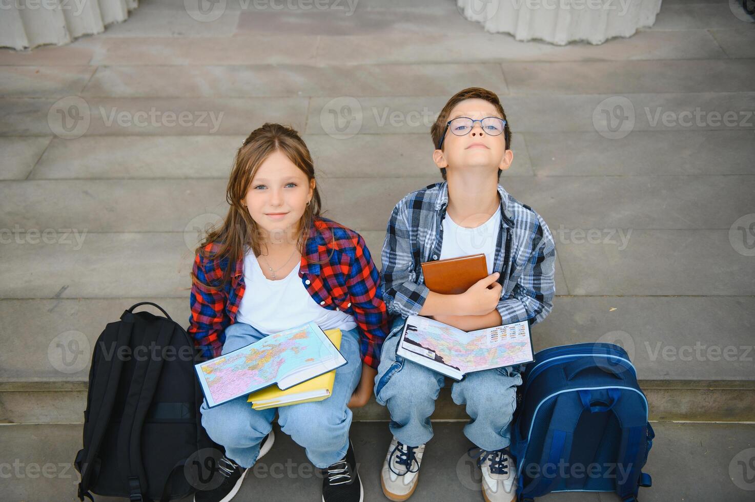 Group of elementary school children reading books having an outdoor class of modern school building background photo