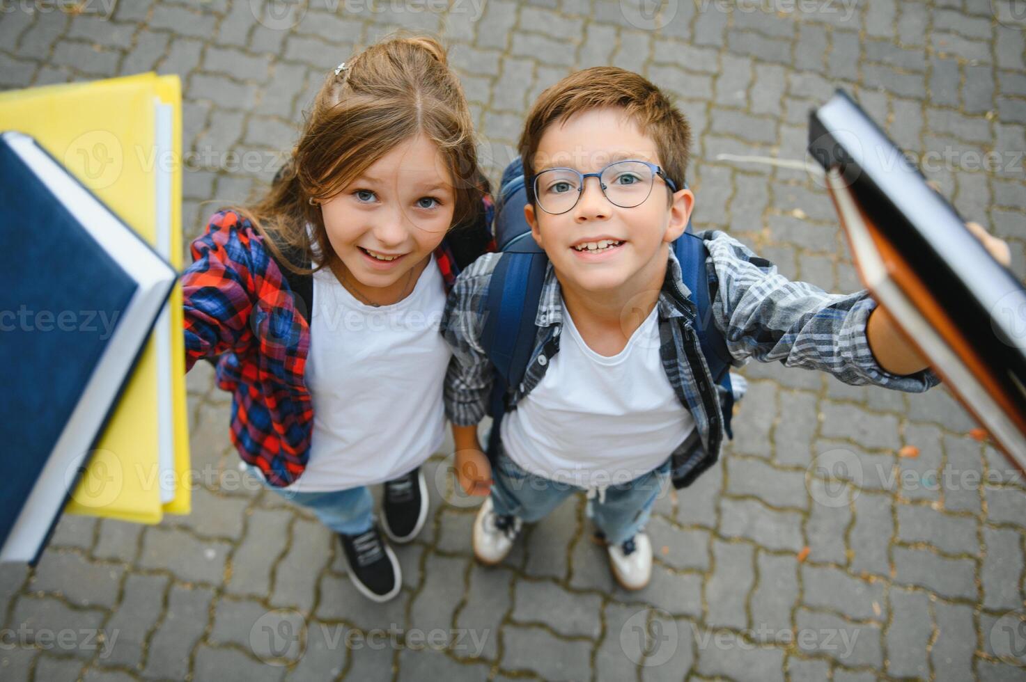 Happy schoolchildren near the school. A boy and a girl are primary school students. School friendship photo
