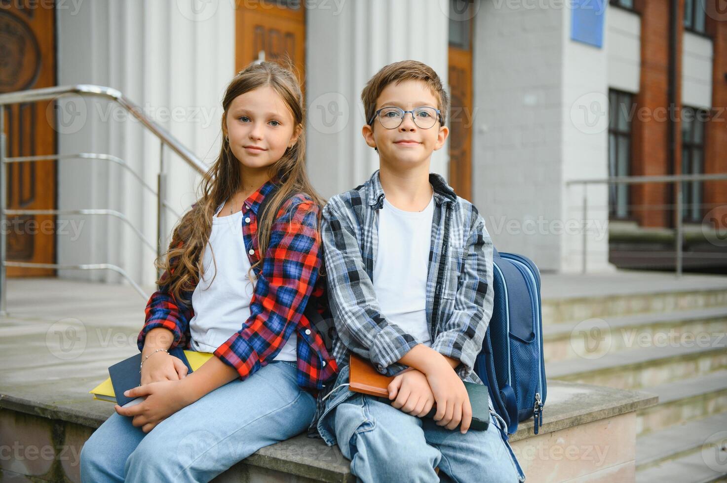 Happy schoolchildren near the school. A boy and a girl are primary school students. School friendship photo