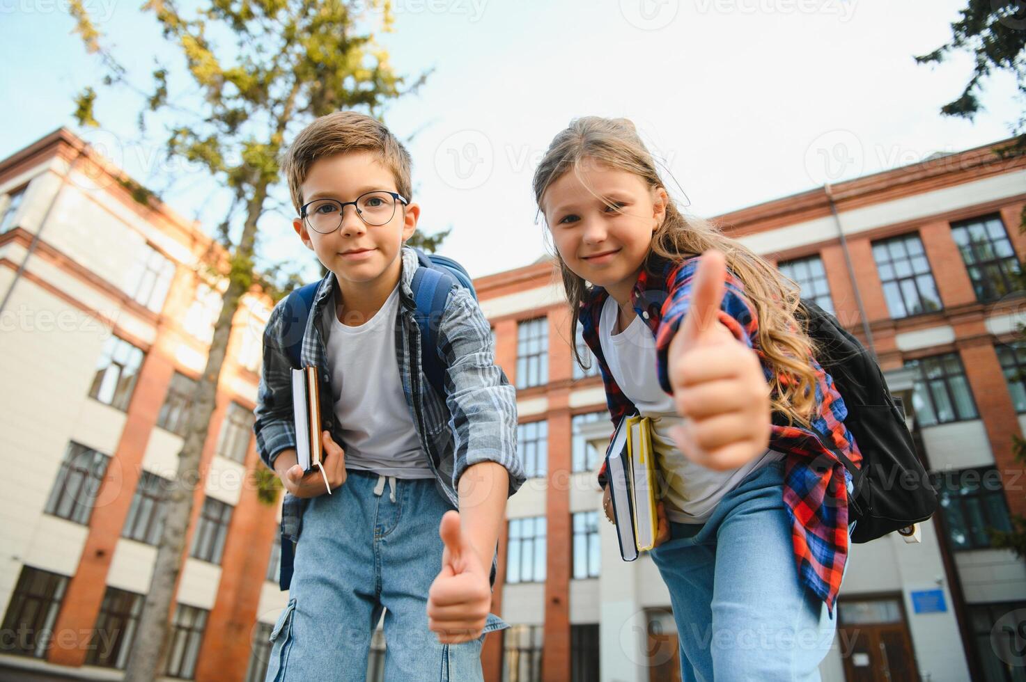Happy school kids friends boy and girl with backpacks walking and laughing having fun together near school building outside outdoor after lessons photo