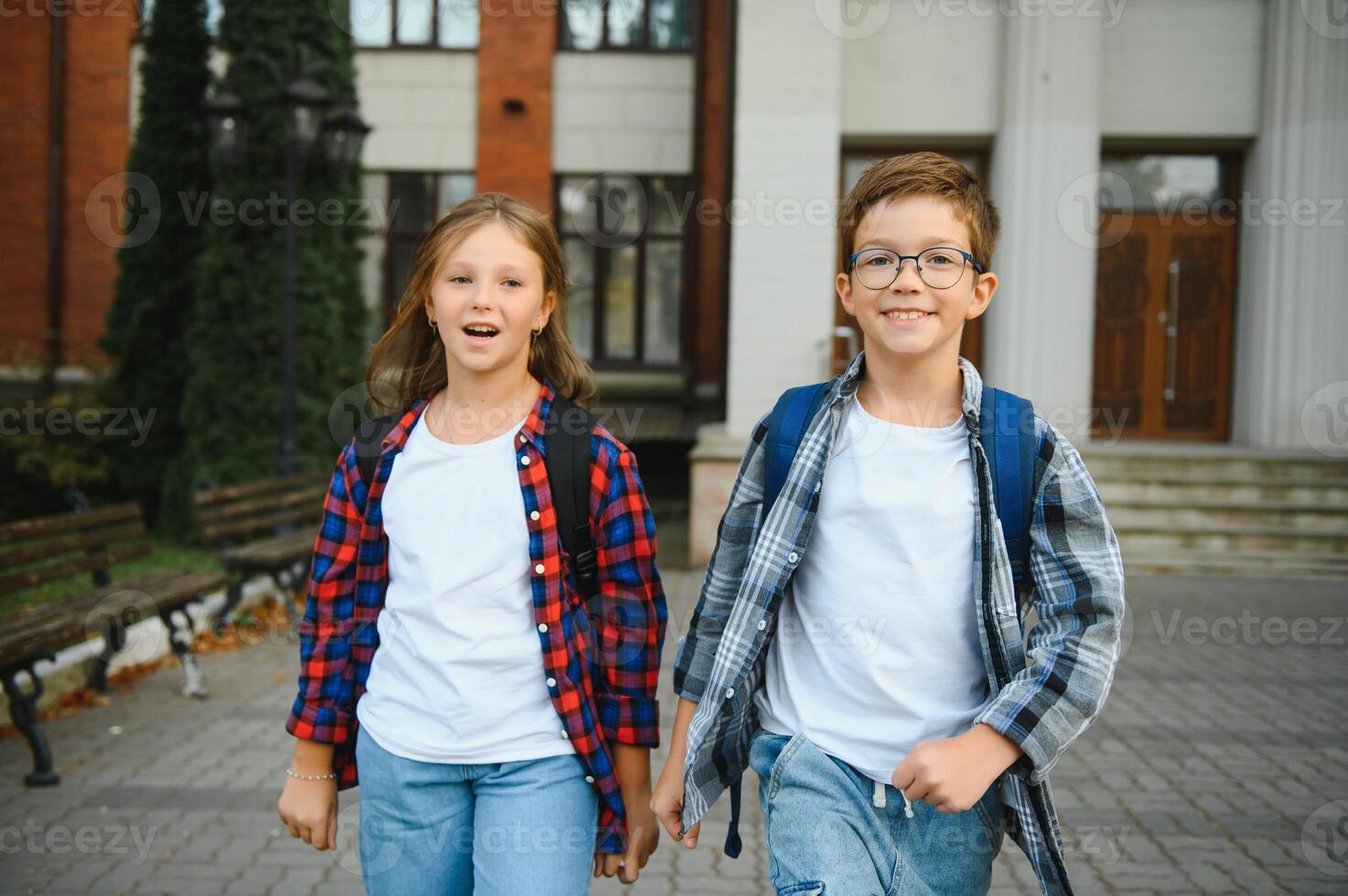 Two, little child with backpack near the school, after finished lesson and speak with each other photo