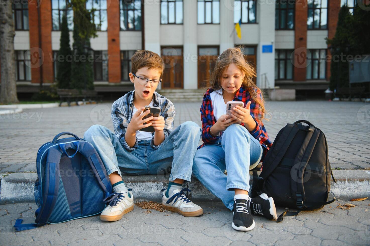 smartphone generation. schoolchildren use a smartphone on the street near the school photo