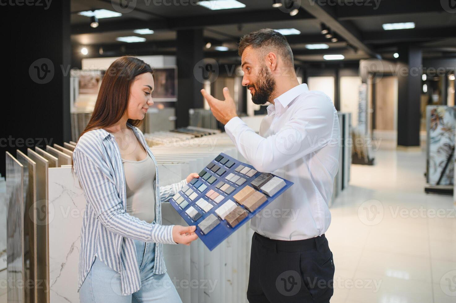 Salesman and a female customer choosing a right ceramic tile for her home, at the home design store photo