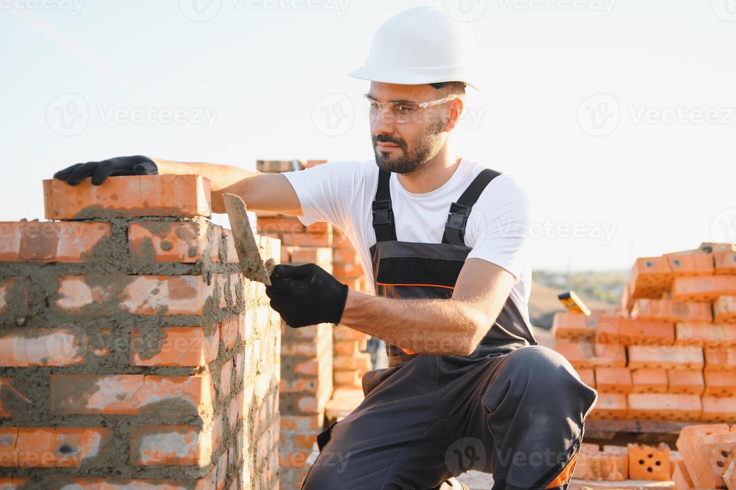 Construction worker man in work clothes and a construction helmet. Portrait of positive male builder in hardhat working at construction site photo