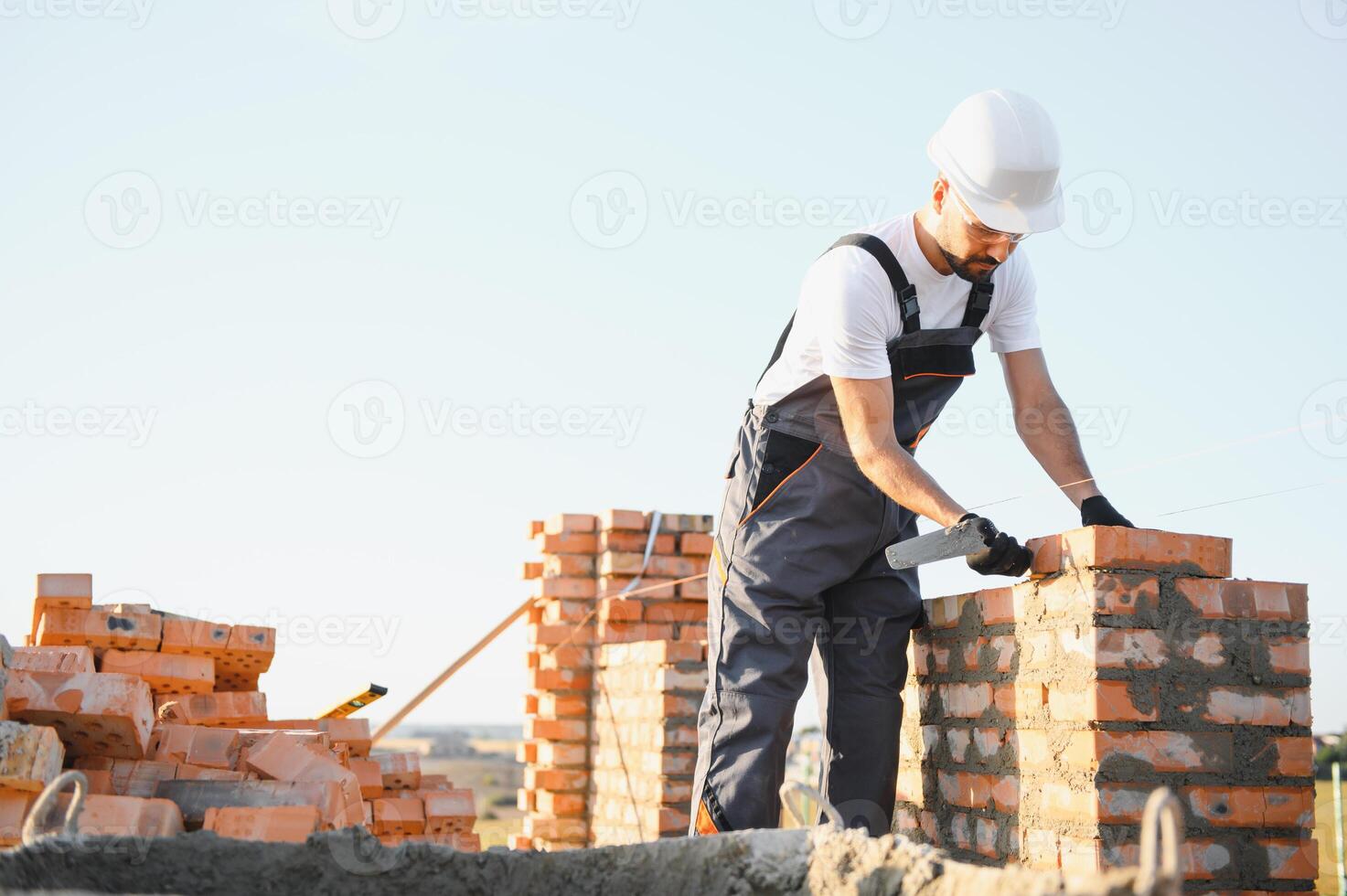 Construction worker man in work clothes and a construction helmet. Portrait of positive male builder in hardhat working at construction site photo