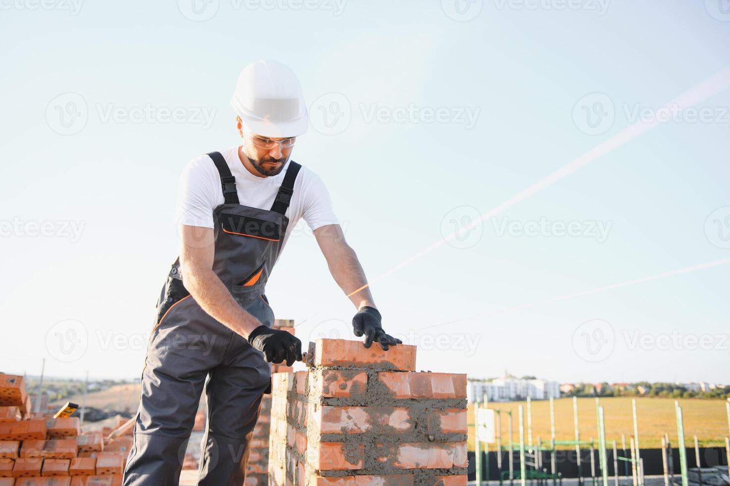 Construction worker man in work clothes and a construction helmet. Portrait of positive male builder in hardhat working at construction site photo