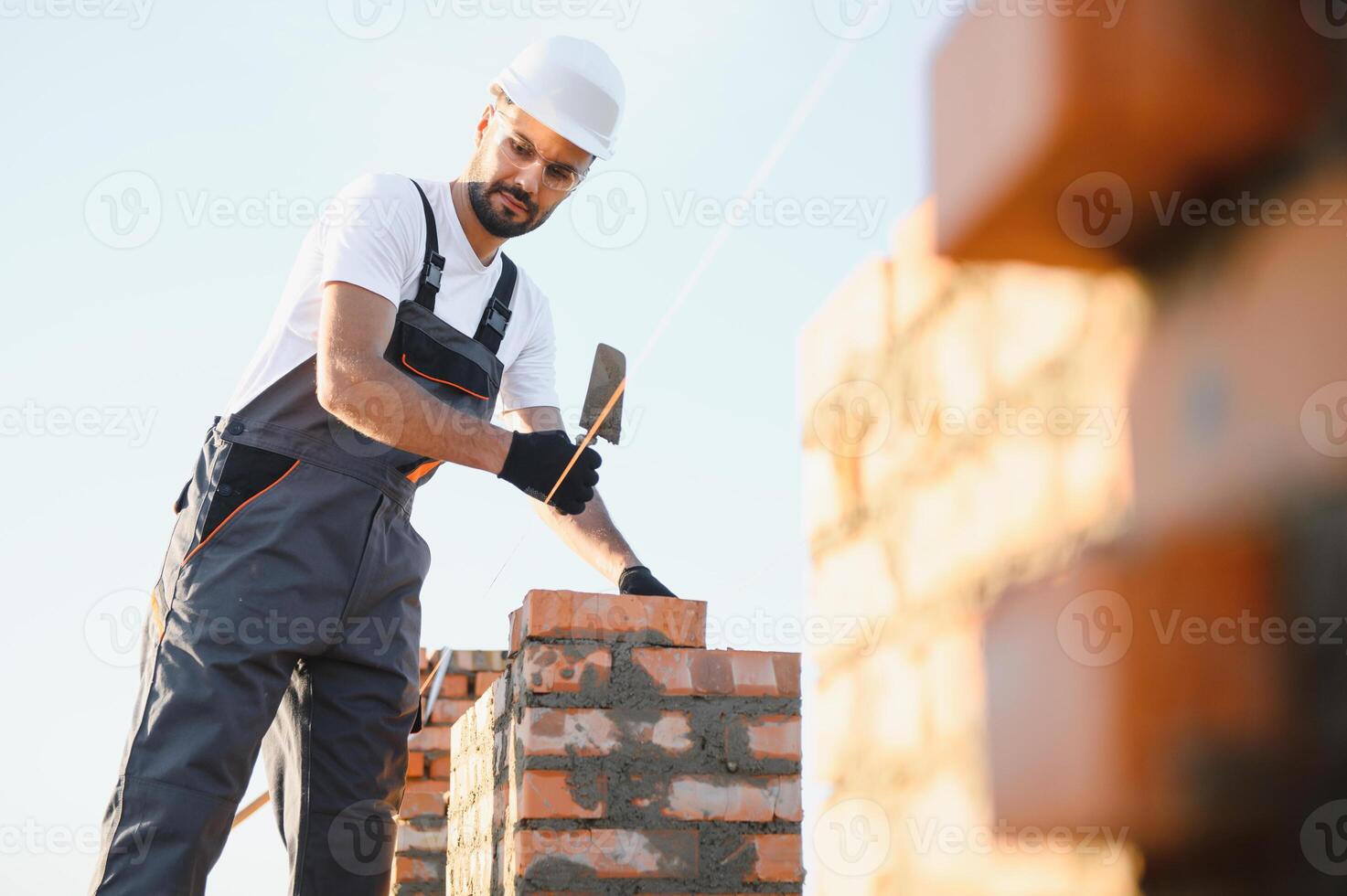 Construction worker man in work clothes and a construction helmet. Portrait of positive male builder in hardhat working at construction site photo