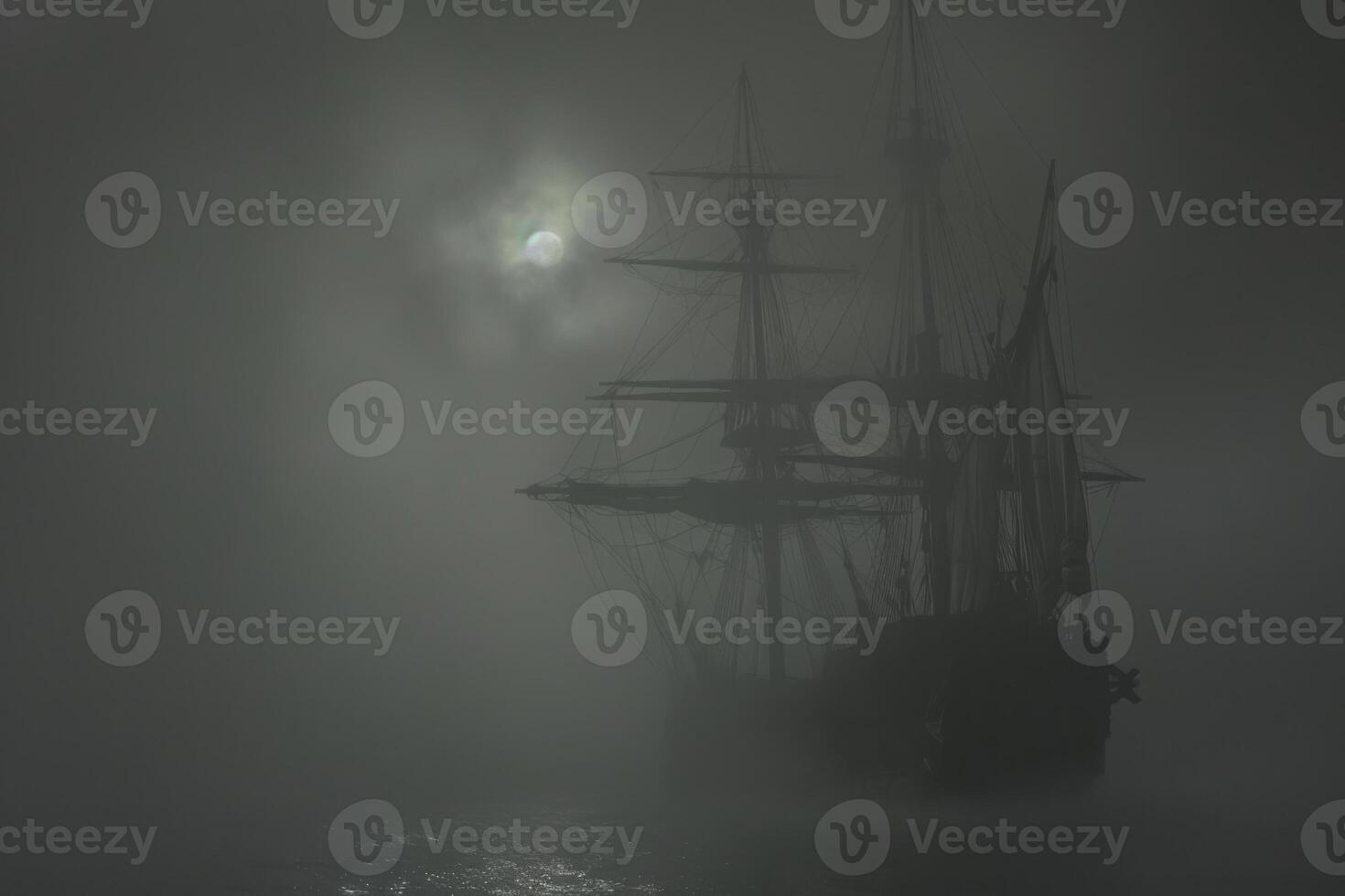A ghostly ship sails through fog under a mysterious moonlit sky at night photo