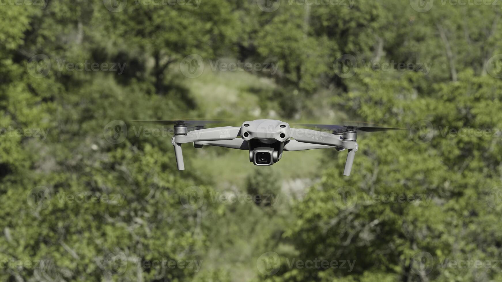 Flying drone in air. Action. Drone flies over green trees. New model of drone in air shoots green trees in summer photo