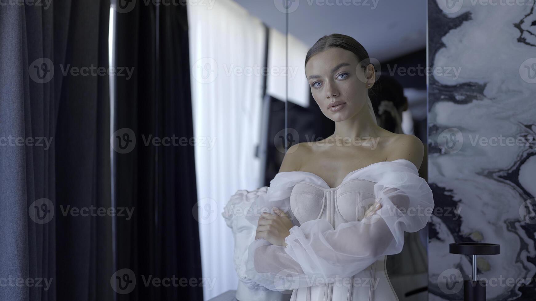 Beautiful elegant bride during photosession indoors. Action. Yong woman in a white dress with corset posing in front of the camera. photo