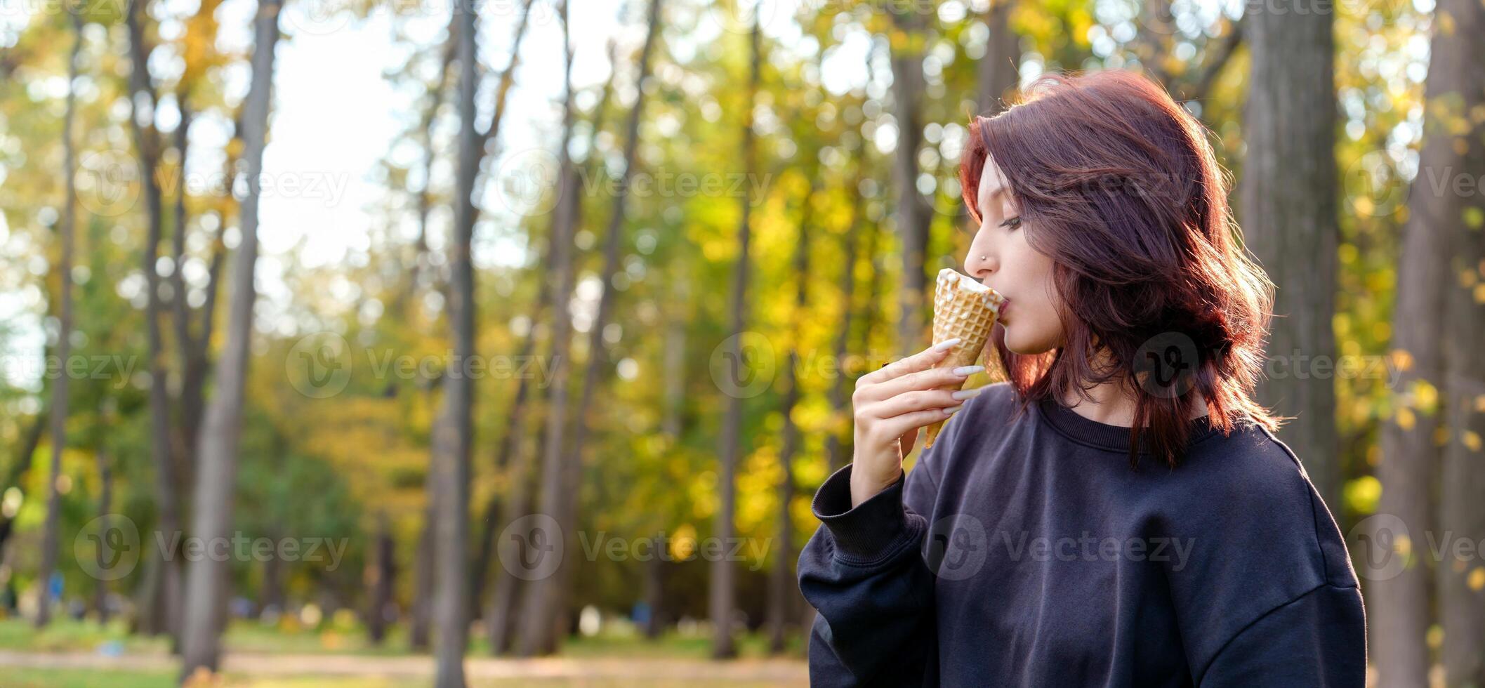 refreshing taste of ice cream brings a smile to the face of a female figure as she licks the frozen confection in a serene outdoor locale photo