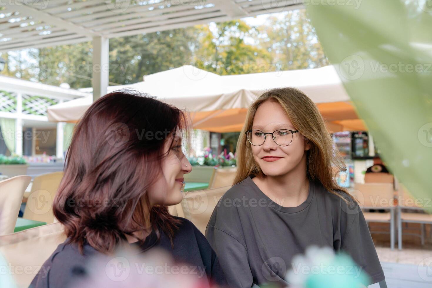 Cheerful female companions casually chatting and sharing a lighthearted moment while waiting for their order at a cozy summer coffee shop, capturing the fun and carefree spirit of friendship photo