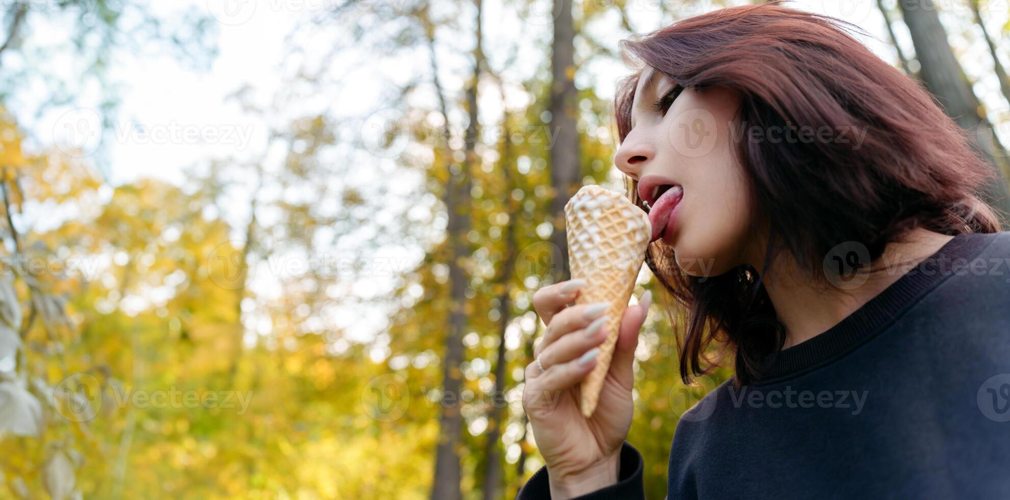 Carefree young woman enjoying a delicious ice cream cone in a tranquil outdoor setting, her expression conveying a sense of pure delight photo