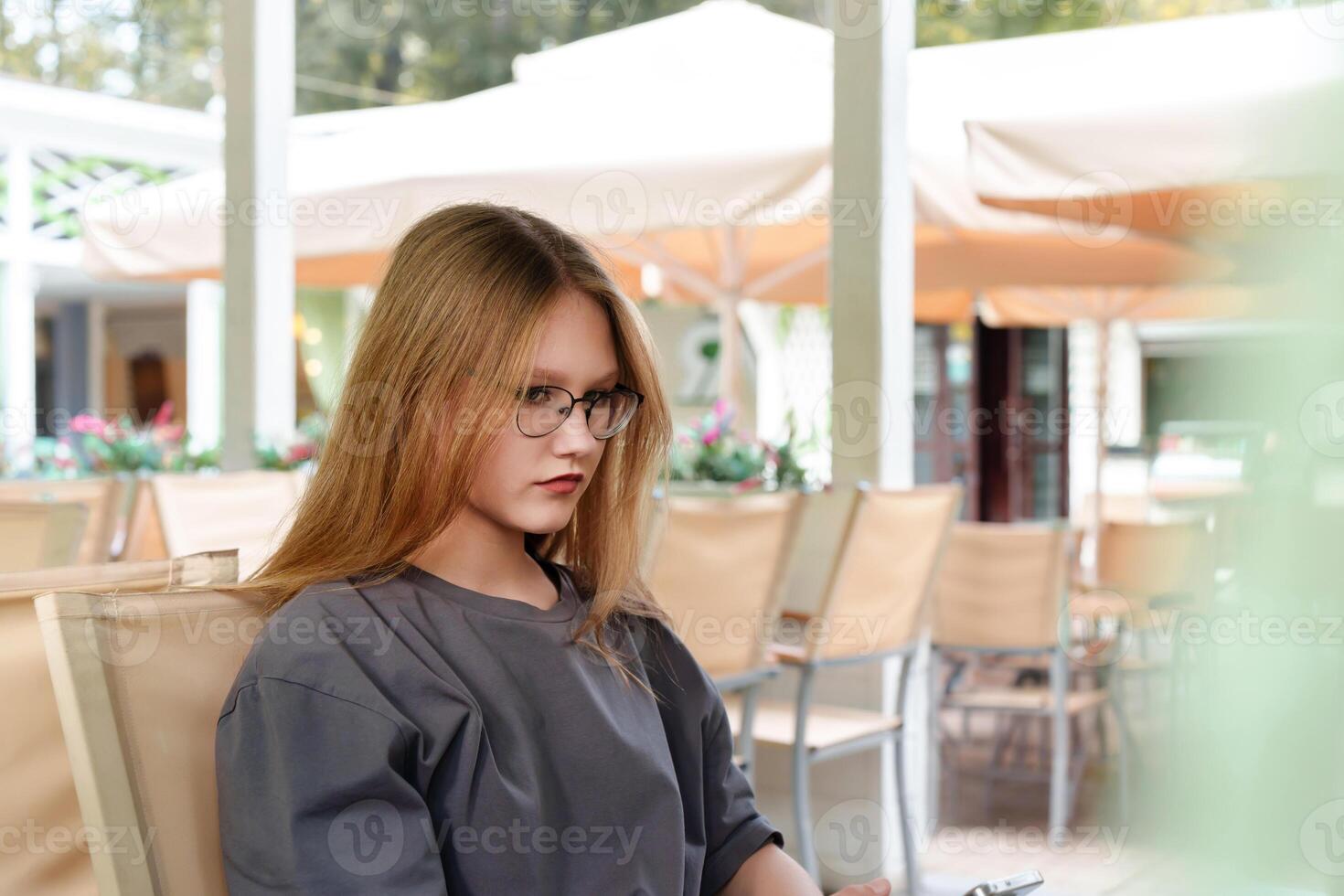 sullen-faced teenage appears offended as she sits alone in a cafe, conveying a sense of annoyance or displeasure photo