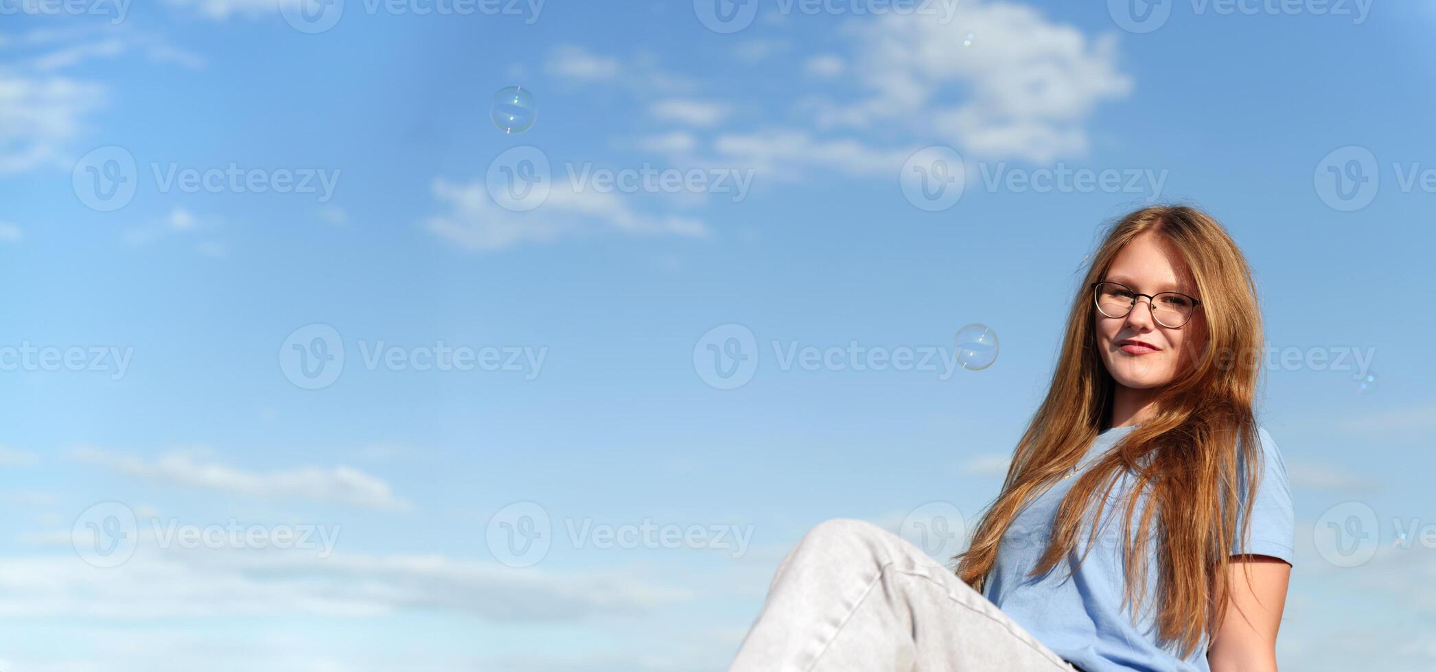 Silhouetted by the vibrant azure backdrop, a female subject's expression is heightened by the presence of her glasses, resulting in a contemplative, enigmatic portrait photo