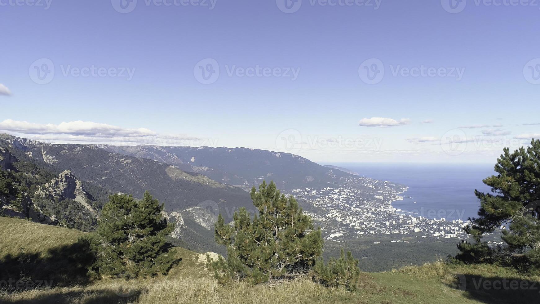 Amazing view from the top on the small city near the sea surrounded by the high mountains and green trees against blue sky in sunny summer day. Shot. Amazing view from above photo