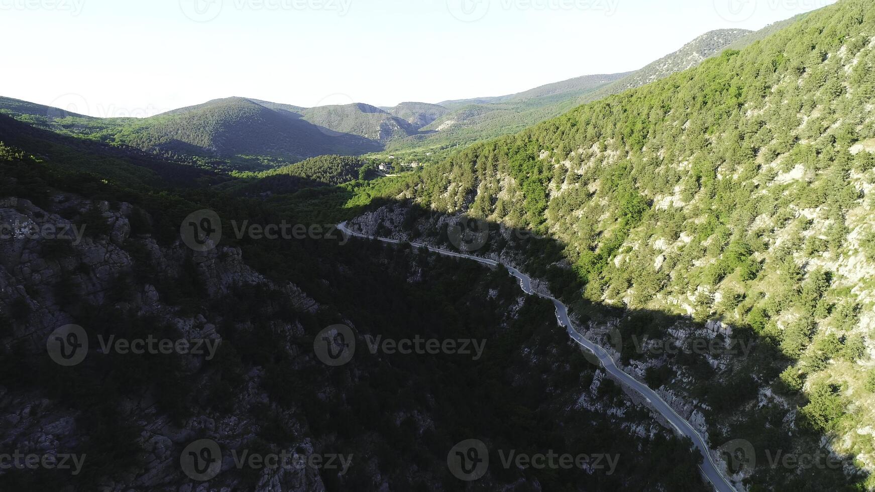 Aerial view of road going through a green mountains covered with shrubs and grass against blue sky in subber day. Shot. Beautiful view from above photo