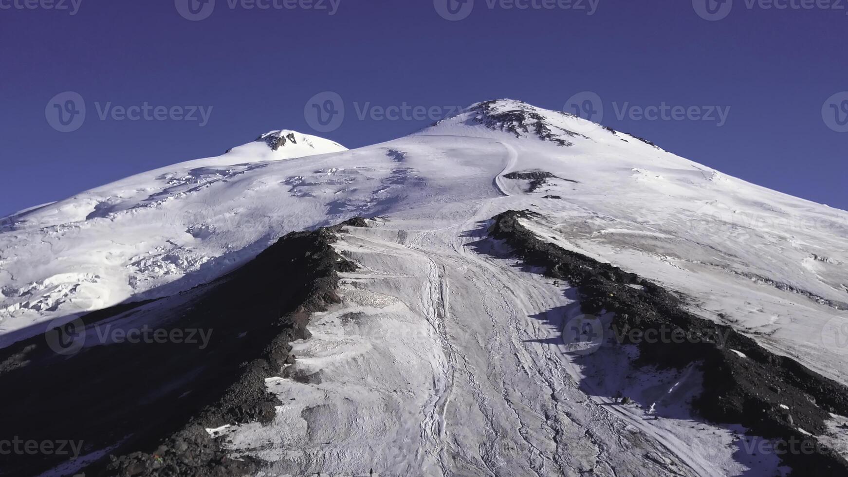 Aerial of snowy mountain peak on blue sky background. Clip. High rock top covered by white snow, natural scenery of french Alps, concept of wild nature. photo