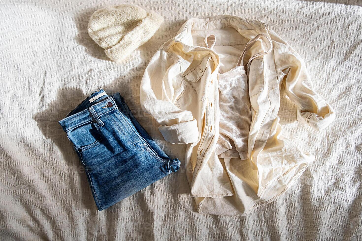 Casual shirt and jeans placed on bed in morning at home. photo
