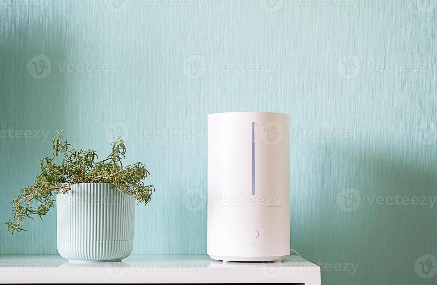 Humidifier with steam coming out from the top on the shelf by potted plant. photo