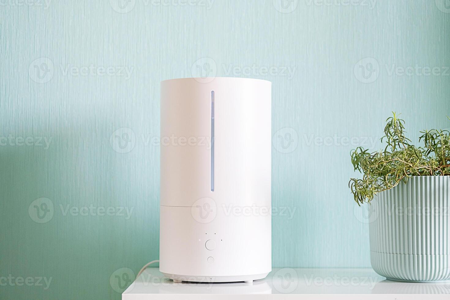 Humidifier with steam coming out from the top on the shelf by potted plant. photo