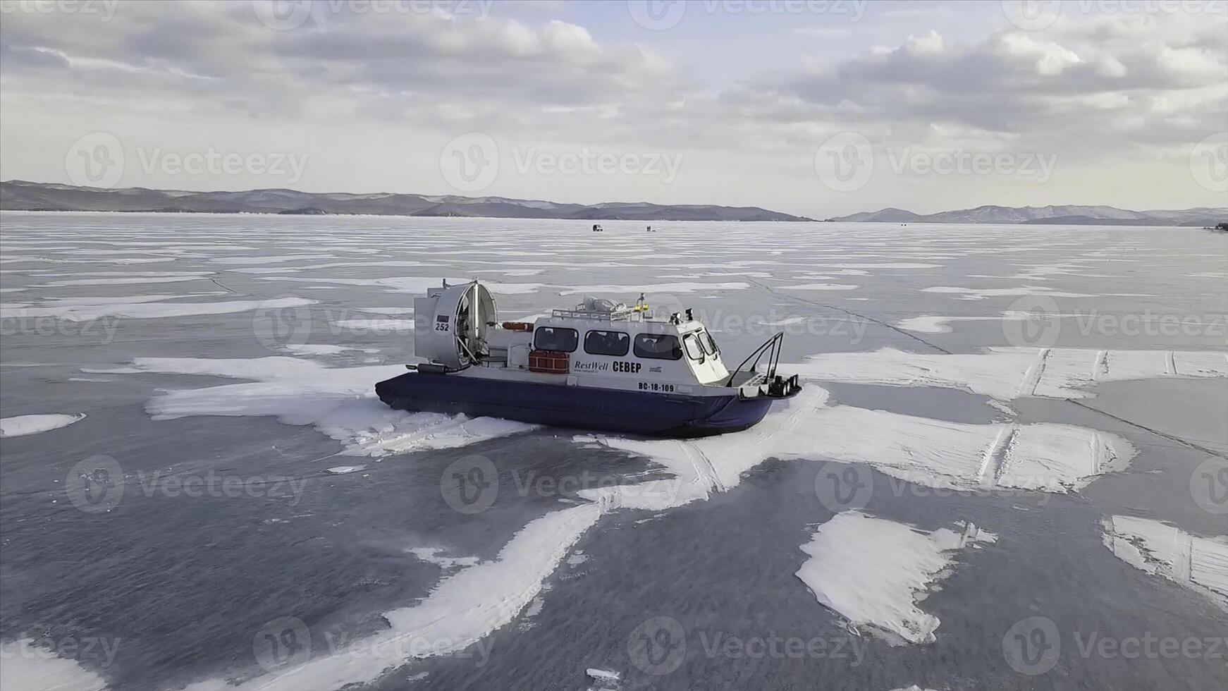 Hovercraft on the ice of lake Baikal in winter time. Clip. Aerial view of the air cushion vehicle on the thick ice of the frozen lake, sports transport and extreme concept. photo